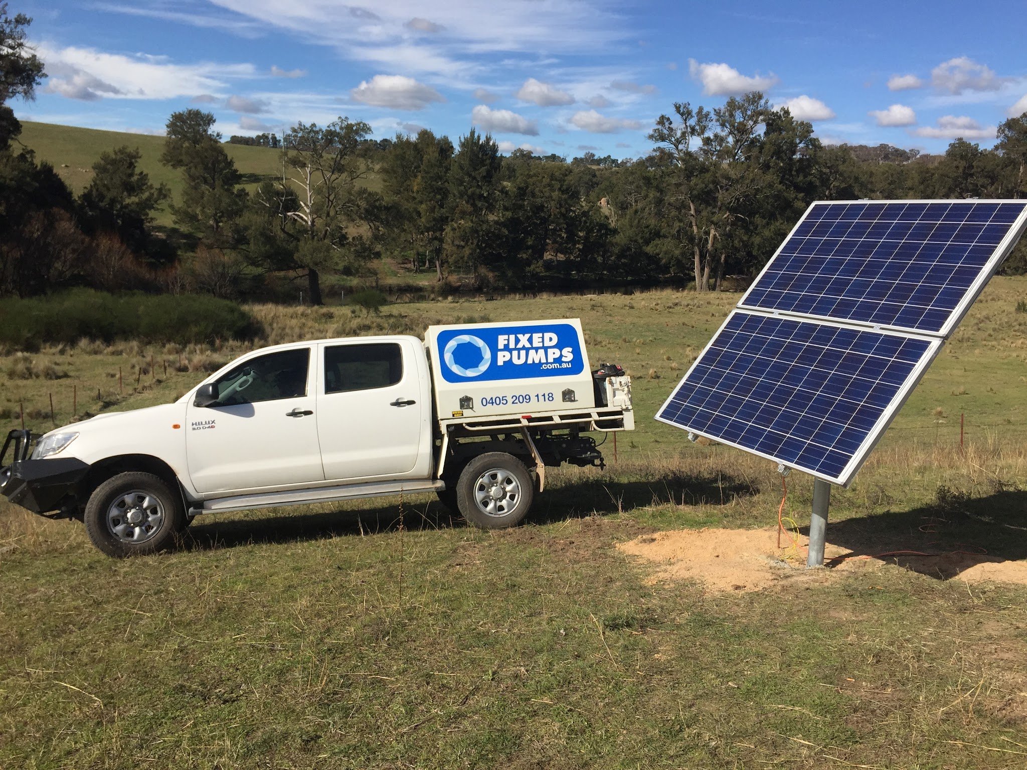 Fixed Pumps Hilux parked beside a two-panel solar pump array in a paddock